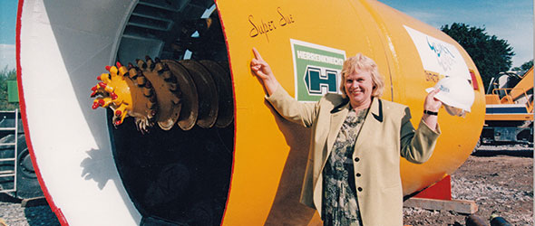 Woman stood in front of a new sewer piping ready to be installed into the ground